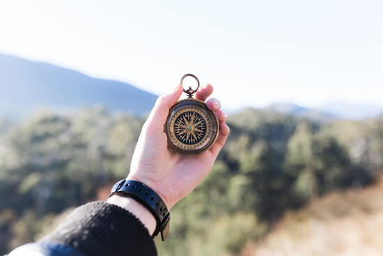 A photograph of a hand holding a compass outside.