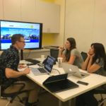 The product team gathered around a table looking at a monitor