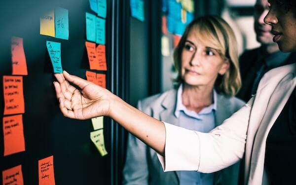 A group of business people looking at Post-it notes on a wall