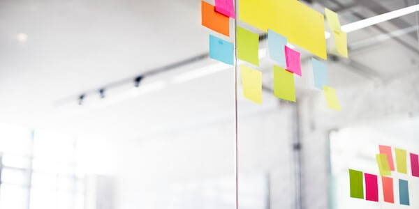 A clear glass wall with colorful sticky notes attached