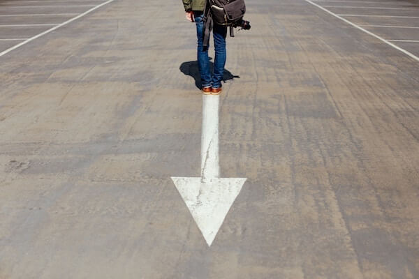 A person standing on top of an arrow painted on the ground