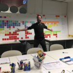 UX Designer Jamieson Hickingbotham standing in front of a white board with hundreds of sticky notes on it