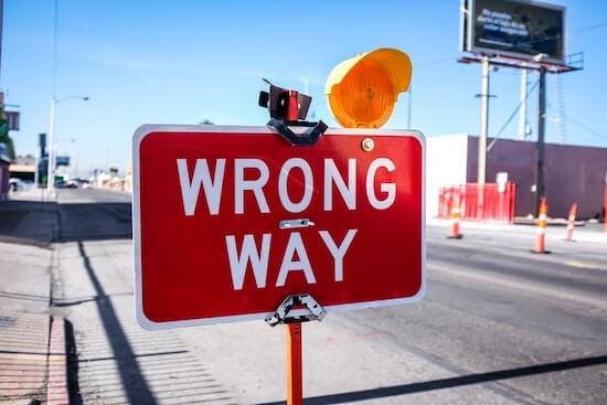 A road sign with the text "Wrong way" written on it.