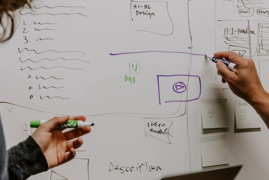 Two people standing in front of a whiteboard and sketching on it