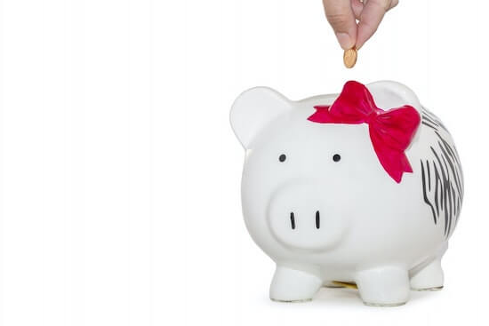 A piggy bank with a hand dropping a coin into it.
