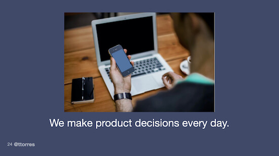 A photo of a person sitting at a desk holding a smartphone and looking at a laptop computer. The caption on the photo reads, "We make product decisions every day."