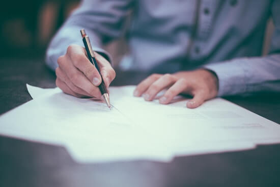 A photograph of a person marking up a document with a pen.