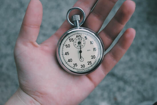 A photograph of a hand holding a stopwatch.