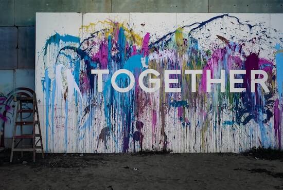 A mural on a wall with paint splatters in different bright colors. The word "together" is written in white on top of the paint.