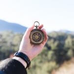 A photograph of a hand holding a compass outside.