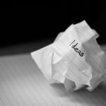 A photograph of a crumpled up piece of paper with the word "ideas" written on it.
