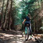 A photograph of a woman on a mountain bike on a trail in a forest.