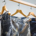 A photograph of several pairs of jeans hanging on a rack.