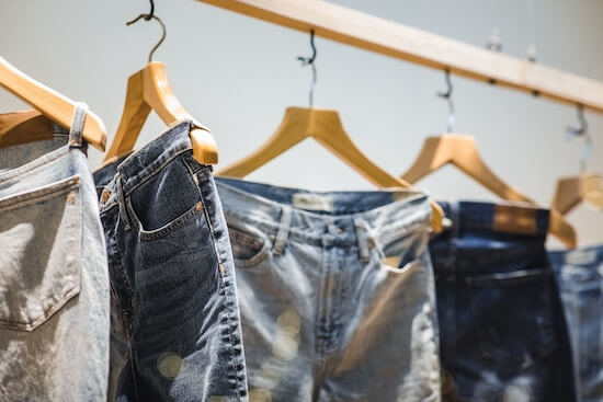 A photograph of several pairs of jeans hanging on a rack.