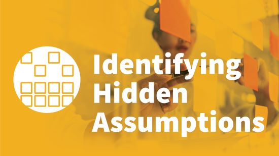 A photograph of a person putting sticky notes on a wall overlaid with the text "Identifying Hidden Assumptions."